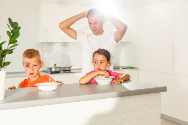 一家人在厨房吃早餐孩子们坐在父亲的腿上图片下载