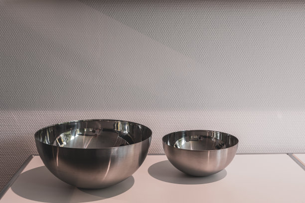 两个不同大小的金属碗并排放在一块白板上图片下载