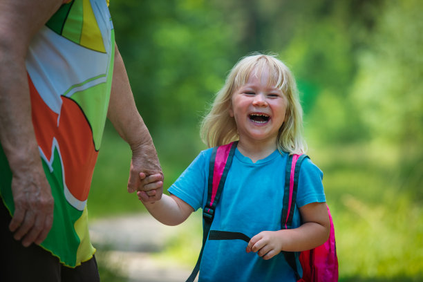 奶奶带着快乐的女孩去上学，可爱的孩子牵着奶奶的手图片下载