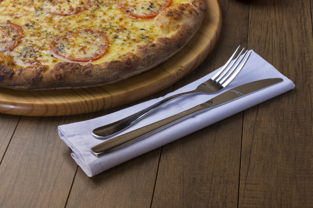 美味的马苏里拉芝士披萨配红番茄片。叉和刀准备使用。水平照片，右下角为文本空间。图片下载