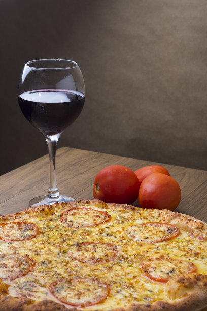 美味的马苏里拉奶酪披萨，配上切片的“u200b”u200bred西红柿。配餐时喝一杯红酒。垂直照片，右上方为文字空间。图片下载