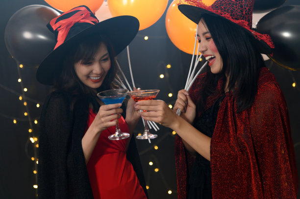 两个美丽的年轻女子在女巫万圣节服装的肖像在派对上黑魔法背景-万圣节派对的概念图片下载