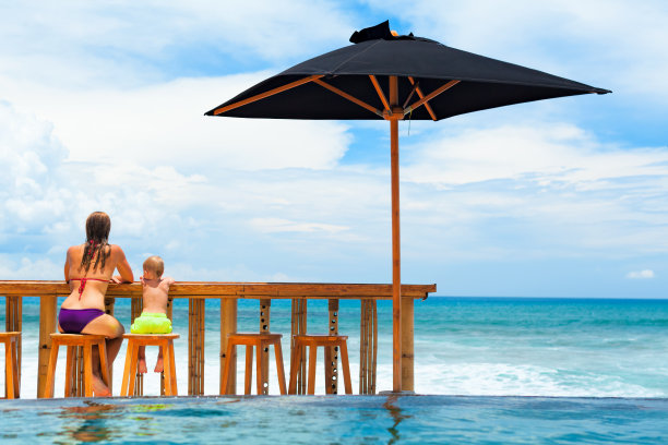 年轻的母亲，快乐的宝贝儿子在泳池边的海滩酒吧放松。图片下载