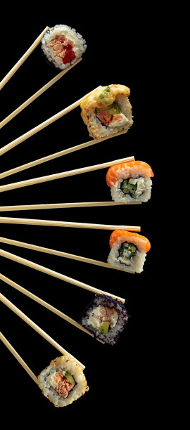 新鲜美味的寿司在木筷子在黑色的背景。图片下载
