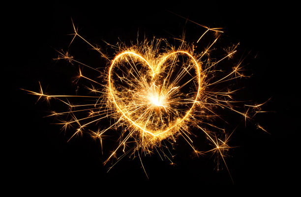 闪闪发光的黄金心孤立在黑色的背景上。图片下载