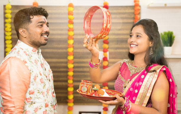 在印度宗教karwa chauth节日期间在家里看到她的丈夫或伴侣之前看到满月穿着传统服装的印度女人。图片下载