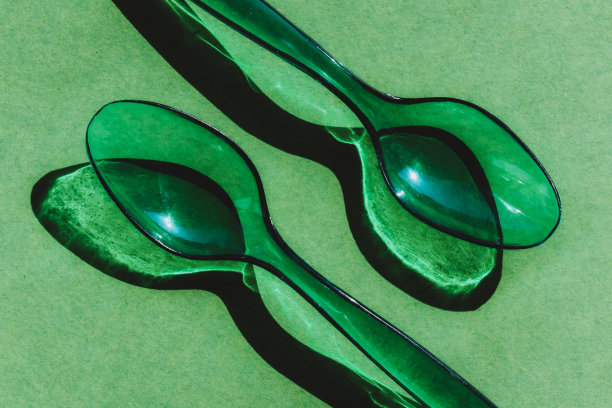 两个绿色透明塑料勺，阴影形成鲜明对比图片下载