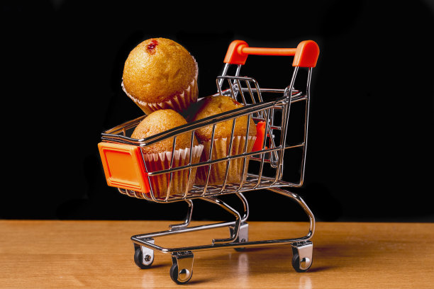 购物车里有美味的松饼。黑色背景的木桌上放着纸杯蛋糕。文本。图片下载