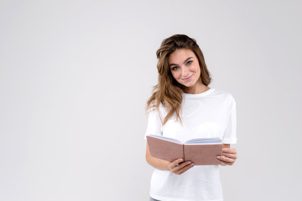 沉思的女人思考新的想法，拿着粉红色的日记，有深思的表达孤立在白色的背景和左边的拷贝空间图片下载