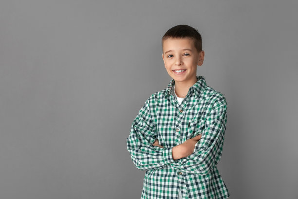 自由泳。男孩孤立地站在灰色的墙上，双臂交叉，愉快地微笑着图片下载