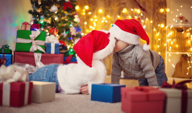男孩和女孩拿着礼物躺在圣诞树旁的地板上图片下载