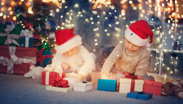 男孩和女孩躺在地板上的礼物靠近圣诞树图片下载