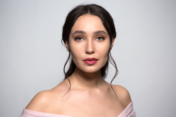 美丽的年轻女子，赤裸的肩膀，灰色背景图片下载