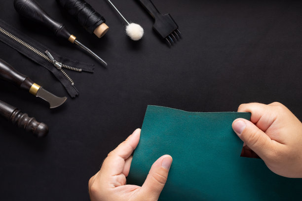 皮革工匠持有绿色皮革样品和工具包的手工艺品钱包素材图片