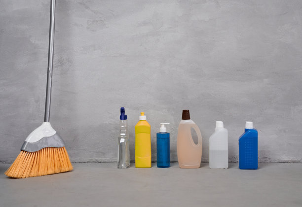 家庭清洁产品和工具。靠灰墙的地板上放着扫帚和装有不同洗涤剂的瓶子图片下载
