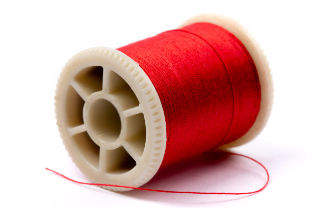 闭合的一个线轴的红色缝纫线躺在它的一边孤立在白色图片下载