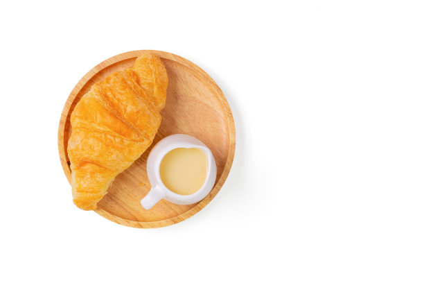 羊角面包加甜炼乳在木切面包板上，白色的背景和剪切路径。法国早餐羊角面包。前视图。图片下载