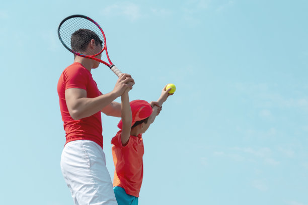 网球教练或教练和儿童网球运动员。儿童体育学校。蓝色的天空背景。横幅。本空间图片下载