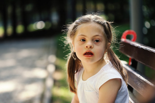 一个漂亮女孩坐在公园长椅上的肖像素材图片