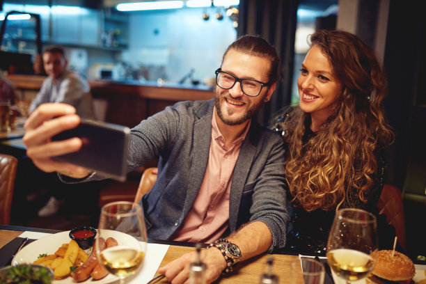 一对迷人的潮人情侣坐在餐厅里自拍。现在是用餐时间。图片下载