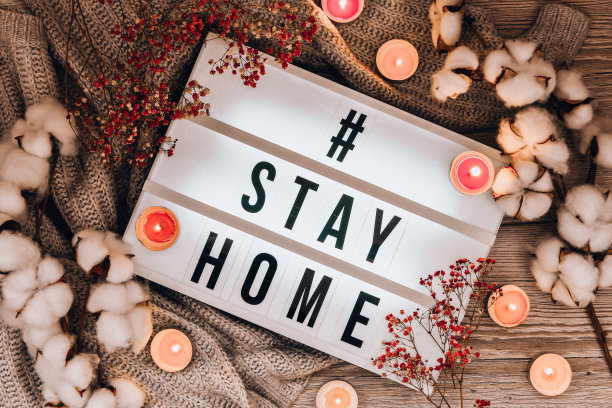 标签留在家里。你的灯箱里的文字，以毛衣、蜡烛、干花装饰和棉花植物为背景。冠状病毒的设备。社会距离。防止大流行图片下载