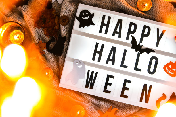 万圣节快乐。文字在白白的灯箱里，配以毛衣为背景，晾干树叶作为万圣节的秋季装饰。鬼，南瓜蝙蝠，黑猫图片下载