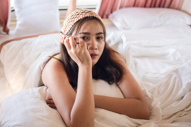 年轻的亚洲女孩戴着头巾在露营车的床上抽烟图片下载