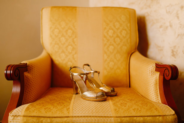 房间里的一把黄色椅子上放着女人的金色高跟鞋。图片下载