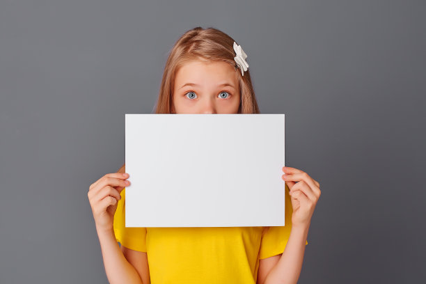 十几岁的女孩在黄色t恤持有空白白纸特写，文字的空间，复制空间图片下载