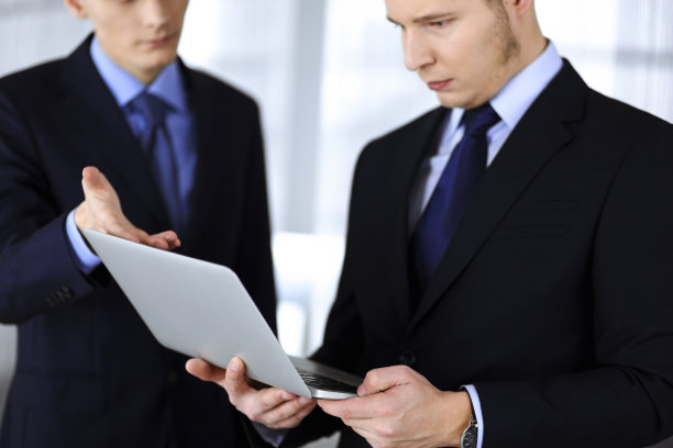 商务人士在会议上讨论演示，站在一个现代化的办公室里。一个不知名的商人和一个同事在电脑上搜索一些信息，律师在谈判。团队合作和伙伴关系概念图片下载