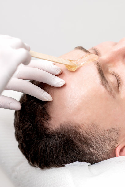 美容师在男性眉毛之间涂蜡图片下载