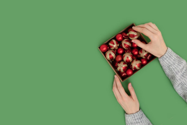 女士从盒子里拿出一个圣诞玩具。图片下载