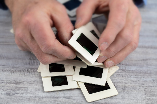 一位老人正在用他粗糙的双手整理一堆35毫米长的旧照片，这表明他已经失忆了图片下载