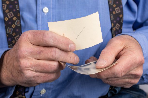 一位上了年纪的男子，粗糙的手里拿着老旧的黑白照片图片下载