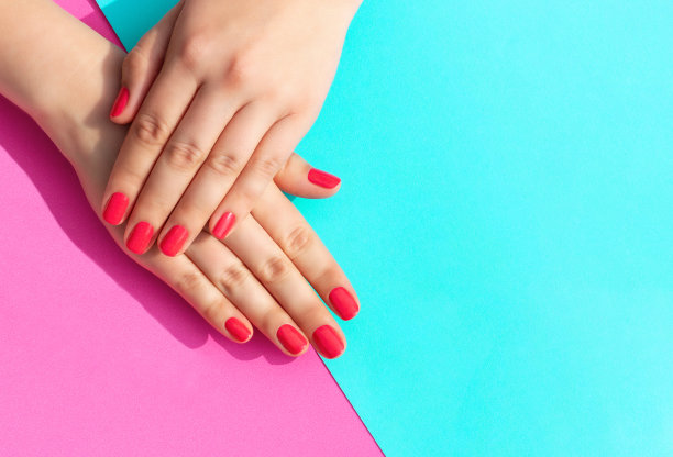 女性的手与指甲在蓝色和粉红色的背景。图片下载