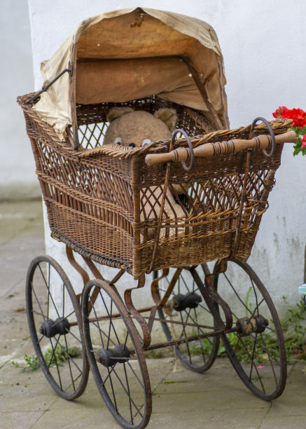 老式柳条婴儿车和泰迪熊。古董柳条婴儿车。图片下载