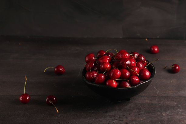 黑色的碗里有新鲜的樱桃，背景是深色的木头图片下载