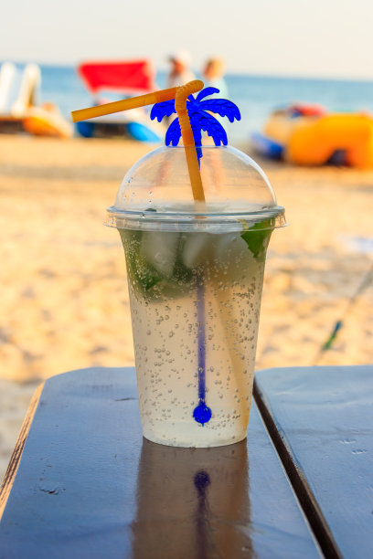 新鲜的莫吉托鸡尾酒放在一张桌子上，背景是热带海滩图片下载