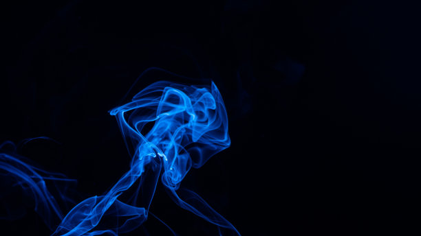 概念图像的蓝色烟雾孤立在黑暗的黑色背景。图片下载