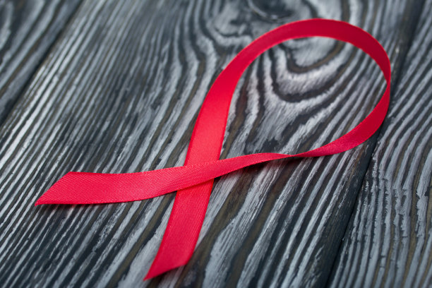 世界艾滋病日红丝带标志。躺在黑色的松木板上。图片下载