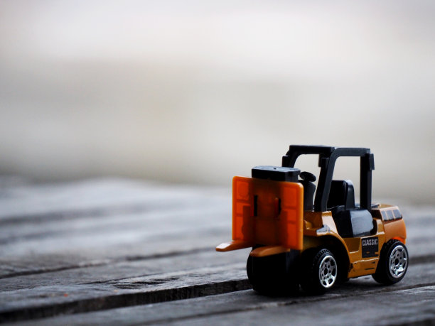 木制桌子上的微型黄色叉车模型。仓储物流业务或建设图片下载