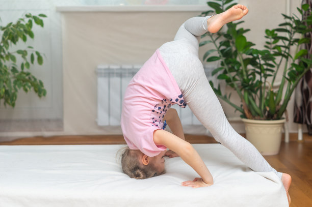 这个女孩是一个在家里做体操和运动的学龄前女孩。头朝下倒立。网络远程学习。闭关锁国则在摧毁隔离。舒适的家的概念。图片下载