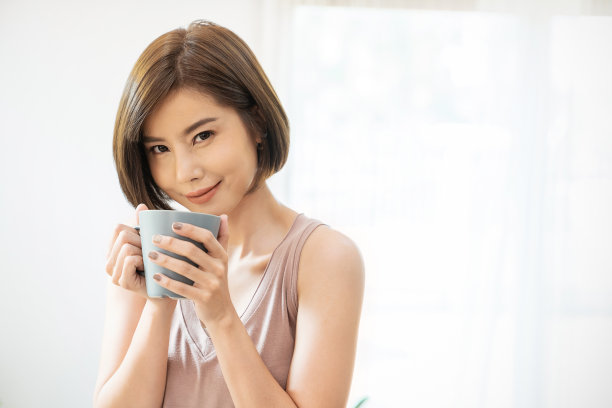 年轻漂亮的亚洲女子在早晨春天手捧咖啡杯，在白色背景下。夏天快乐的放松时光。韩国化妆唤醒日常，亚洲生活方式概念图片下载