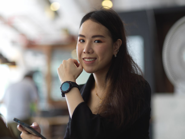 女商人穿着黑色套装，戴着智能手表，微笑着看着相机图片下载