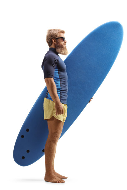 一个蓄着胡须的金发年轻人拿着冲浪板的完整的侧面照片图片下载