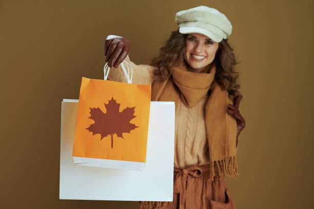 微笑的40岁家庭主妇在毛衣孤立的米色图片下载