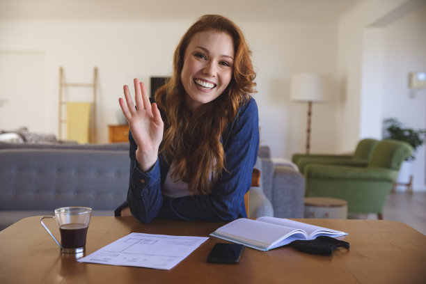 女人坐在家里的桌子上挥手的肖像图片下载