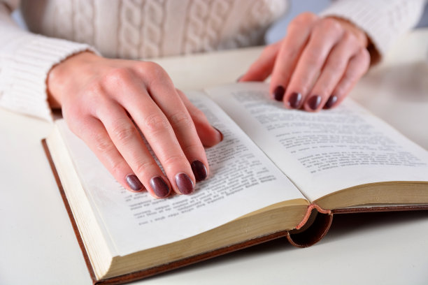 近距离女人的手在书和棕色指甲油上的女孩的手指图片下载