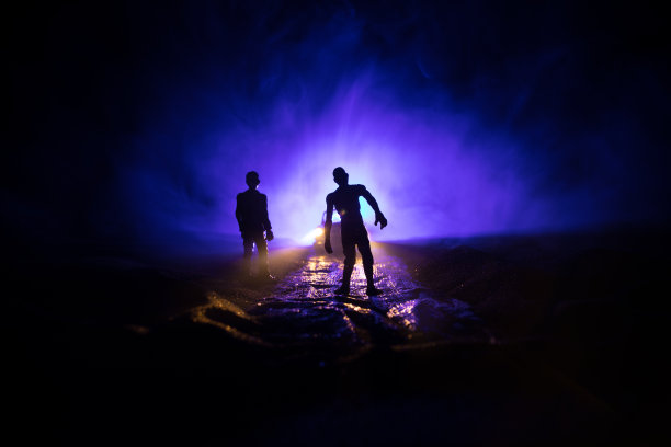 一辆停在路上的车点燃了僵尸的照片。可怕的僵尸剪影夜晚附近的汽车。小型装饰。图片下载