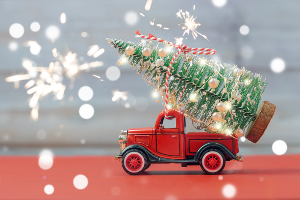 红色复古小玩具卡车与闪闪发光的散景和烟花送圣诞树的卡车车身在红色和灰色的背景。图片下载